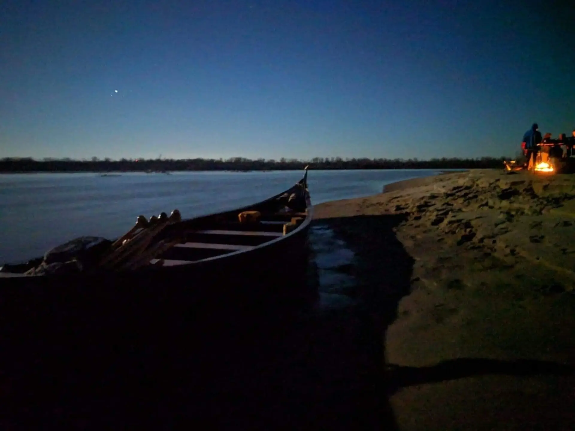 Quapaw voyageur canoe on the Mississippi at night with campfire