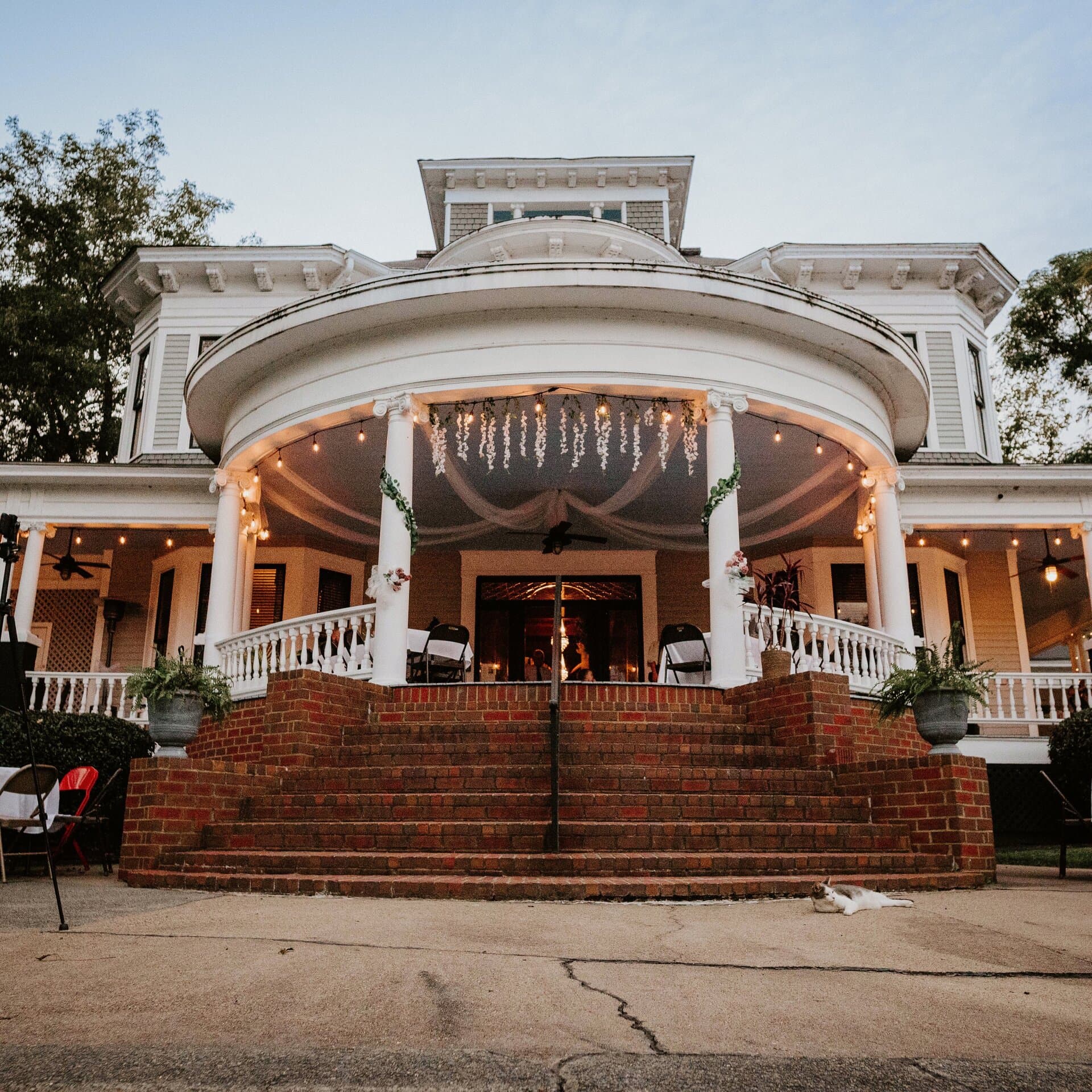 The wraparound porch decorated for an event at dusk